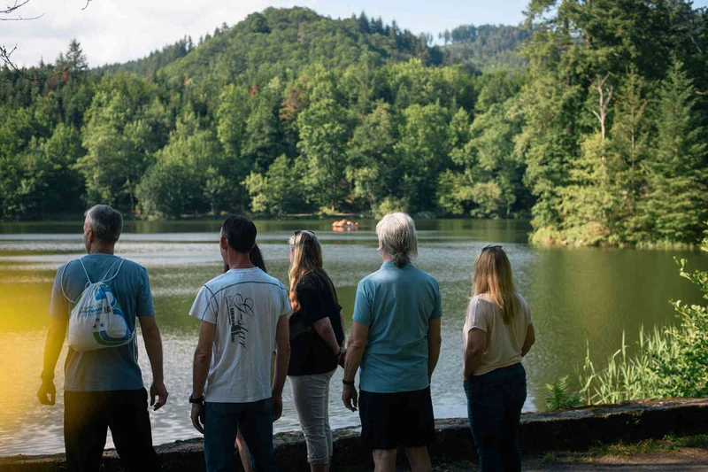 Gruppe von Menschen stehen am see und schauen aus wasser