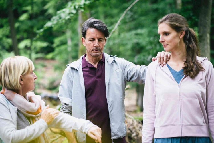 Mann steht in einer gruppe und h&auml;lt sich fest