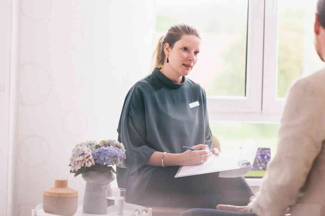 Frau spricht mit Patient und macht notizen